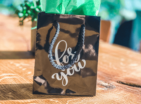 Stijlvol geschenktasje op een houten tafel. Opschrift van het tasje: for you